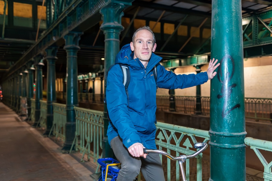 Man op OV-fiets steunt met een hand tegen groene pilaar bij station Haarlem.